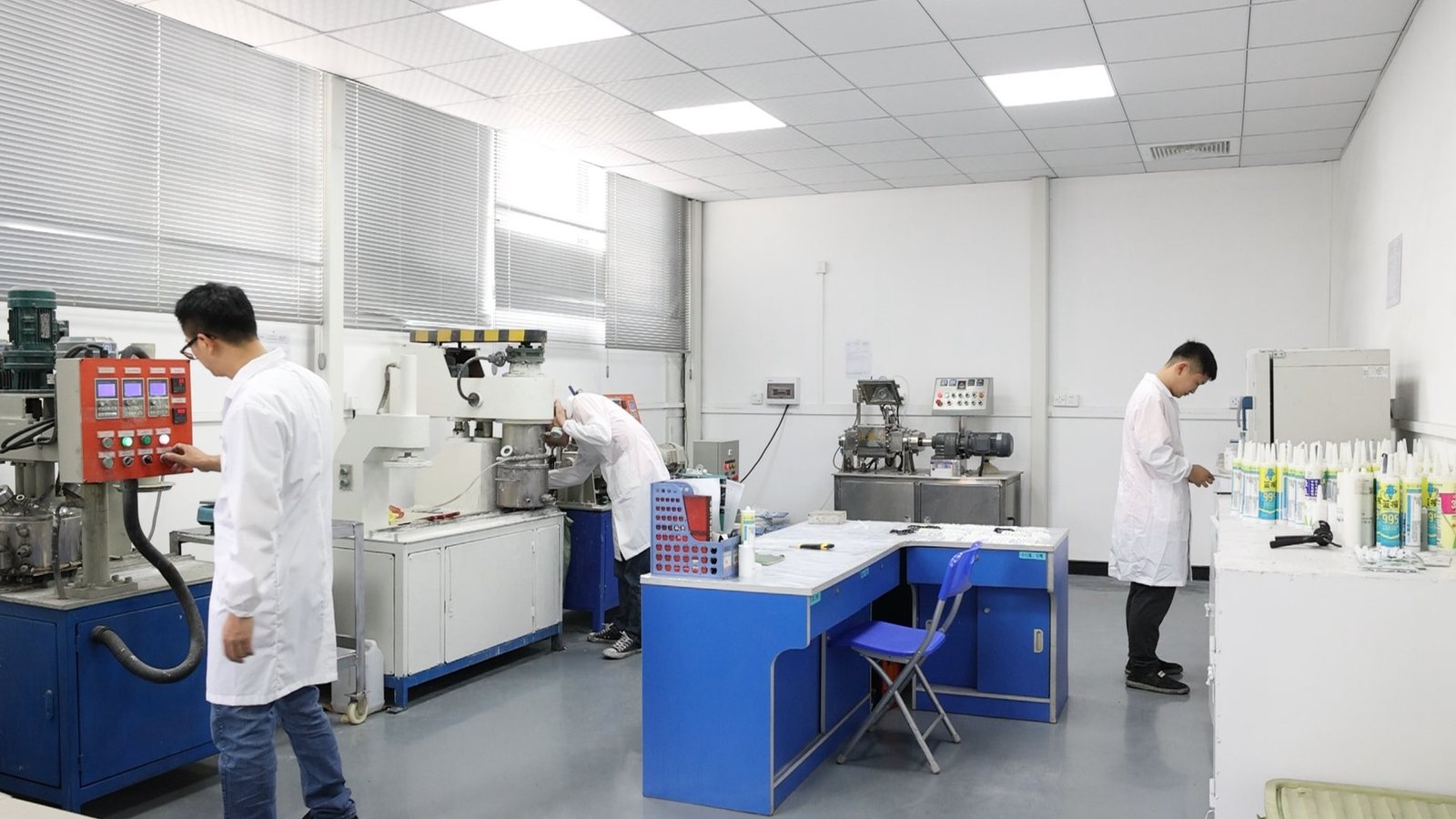 Factory laboratory with staff working at sealant preparation equipment