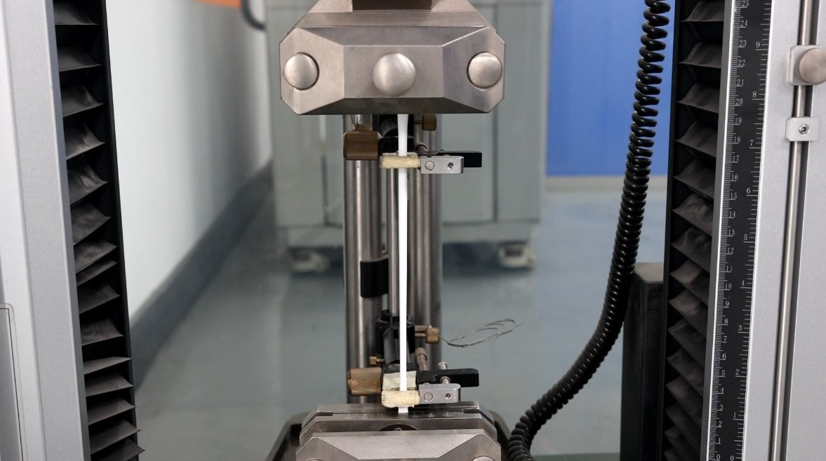 Prepared white sealant specimen mounted in tensile test equipment