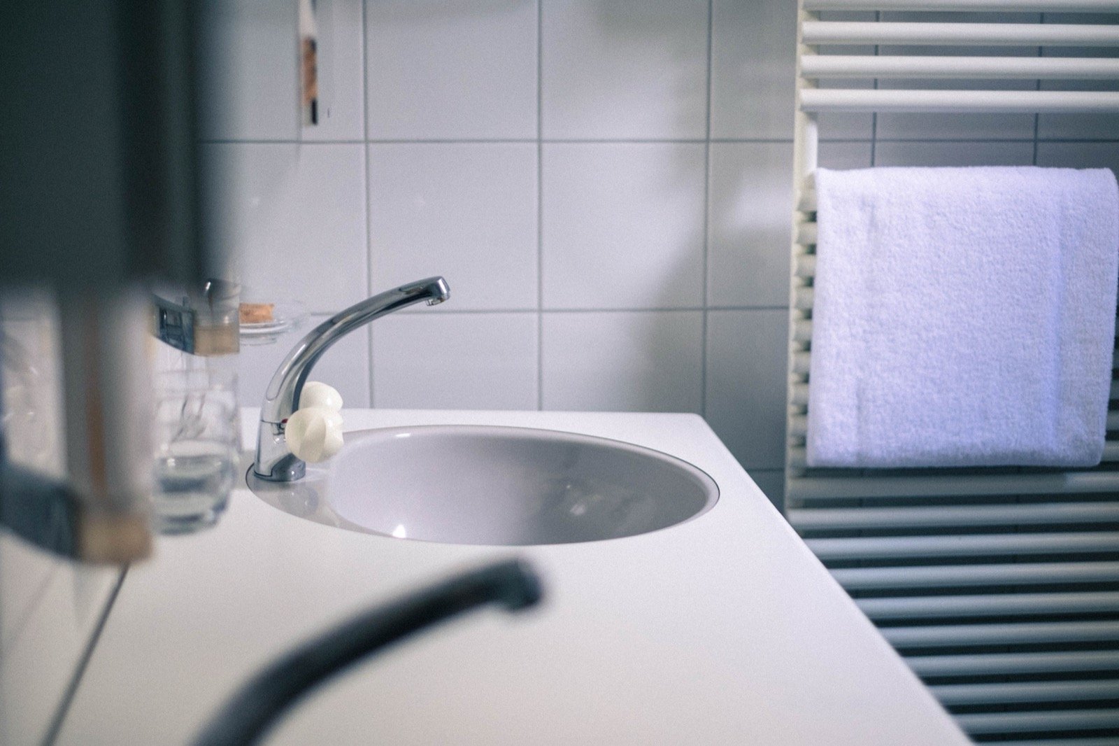 Tiled bathroom vanity with a white basin, faucet and tiled wall.