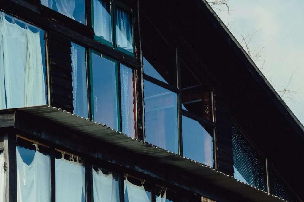 Exterior view of large glass windows set in a dark residential facade.