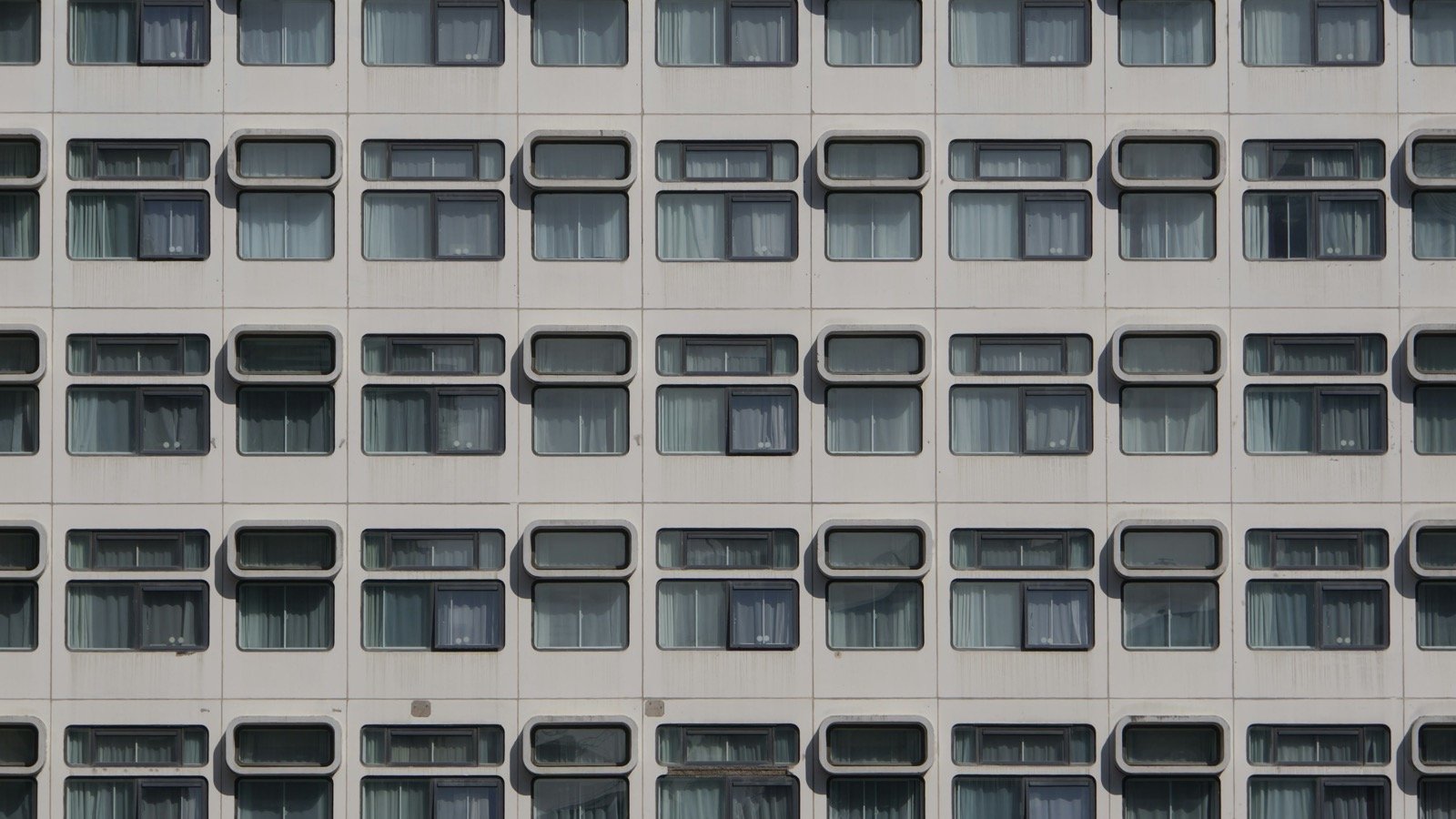 Repeating rows of window openings and facade panels on a multi-story building.