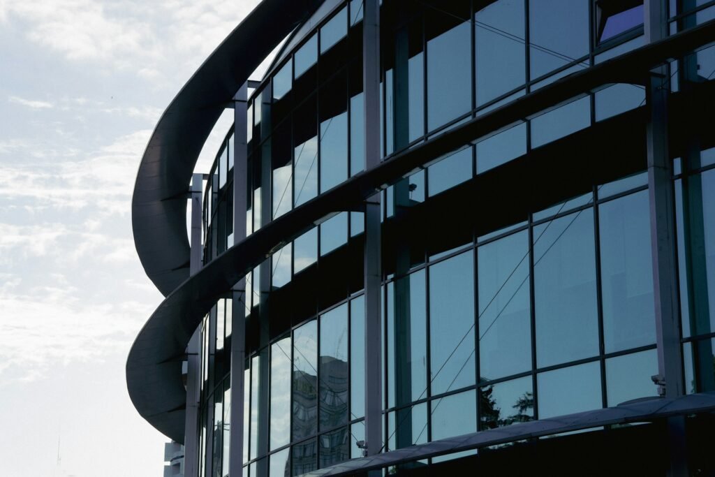 Glass curtain-wall facade with dark mullions, reflective windows and visible panel joints.