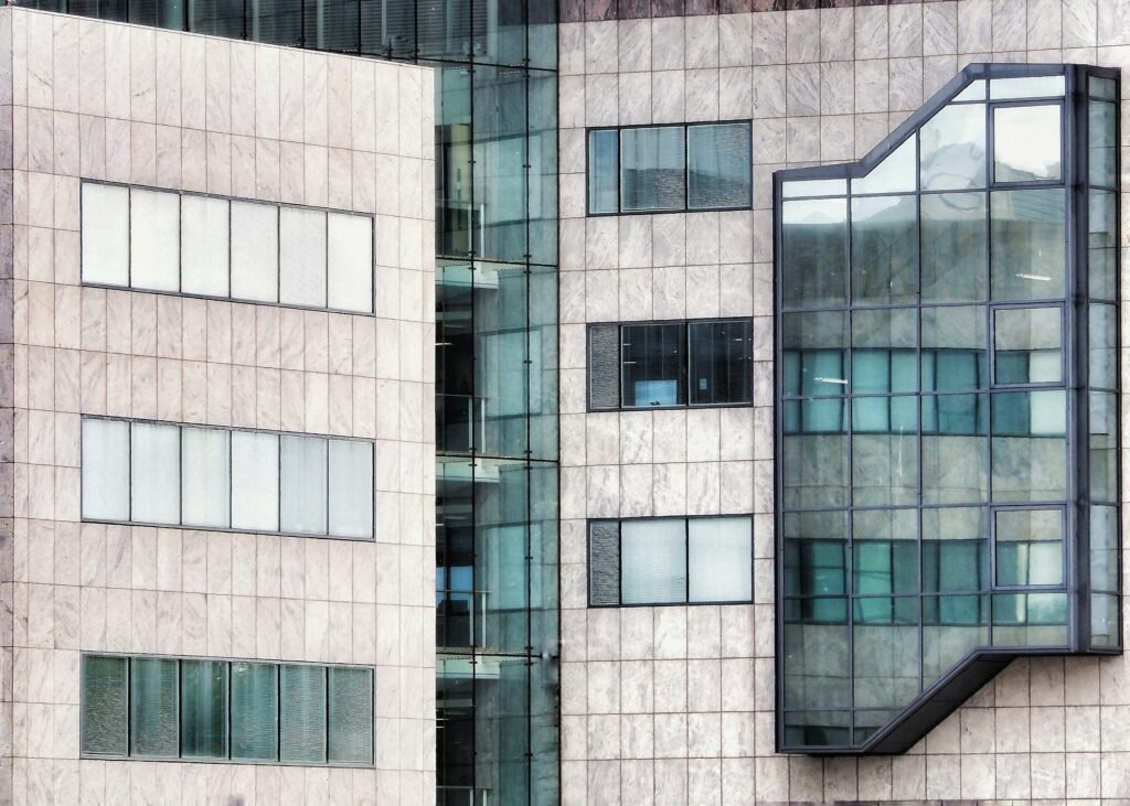 Modern stone-clad facade with reflective glass curtain wall and window panels.