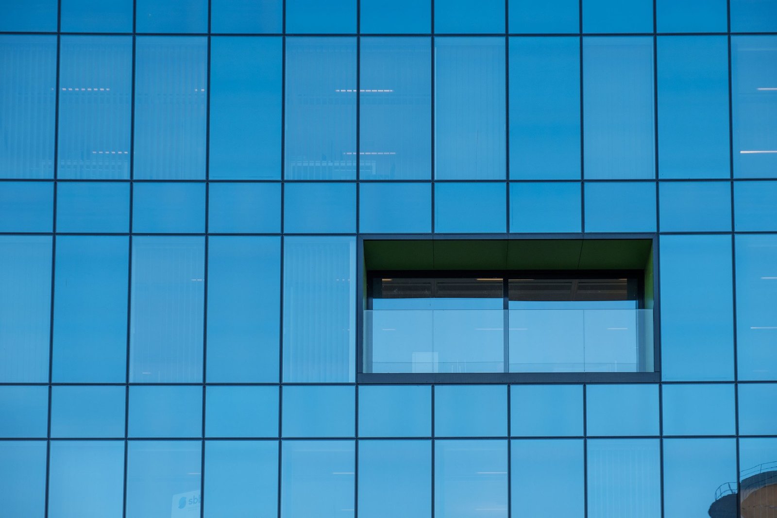 Close-up of glass facade panels with dark framing and reflective window joints.