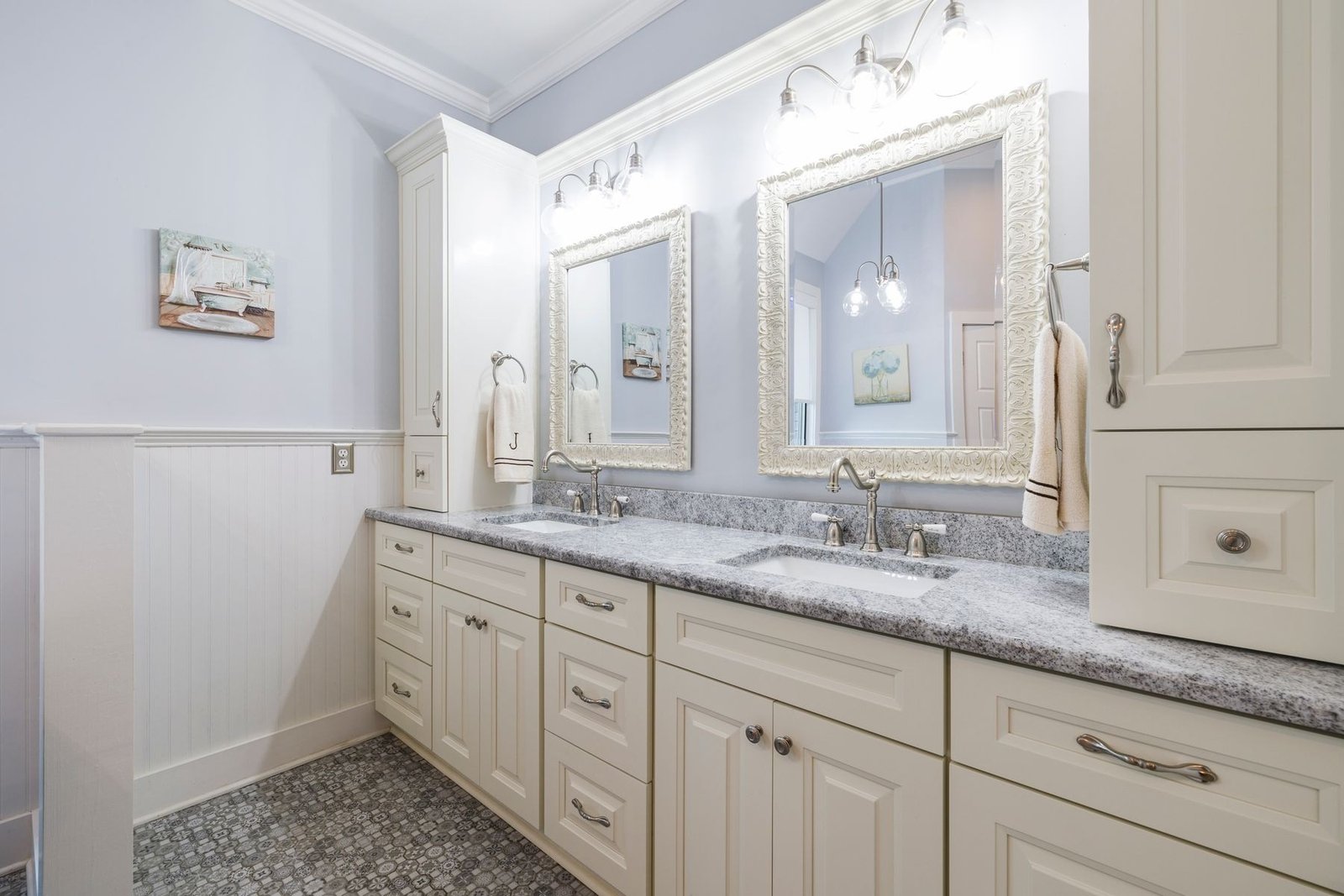 American-style bathroom with a gray granite double vanity, white cabinets and framed mirrors.