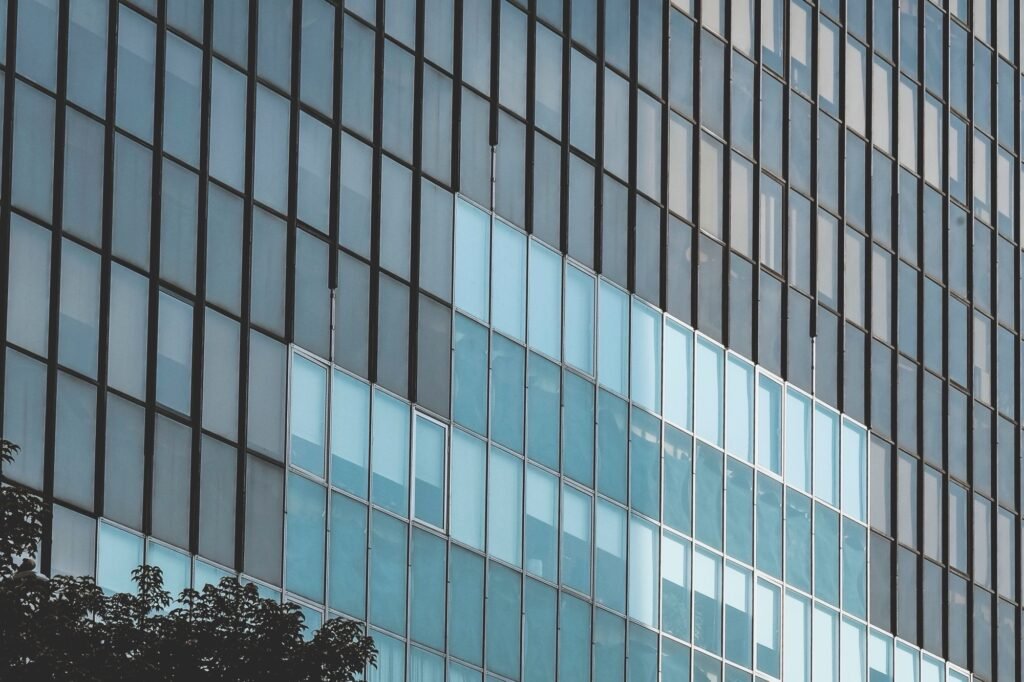 Close-up of blue glass curtain wall panels divided by dark framing and joint lines.