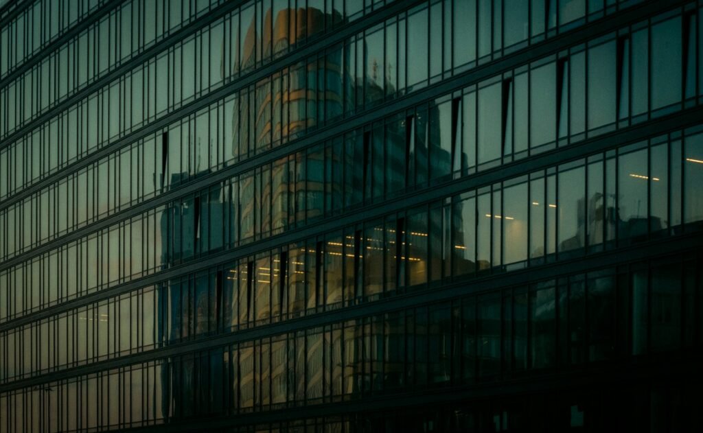 Glass facade with vertical window mullions and a reflected building.