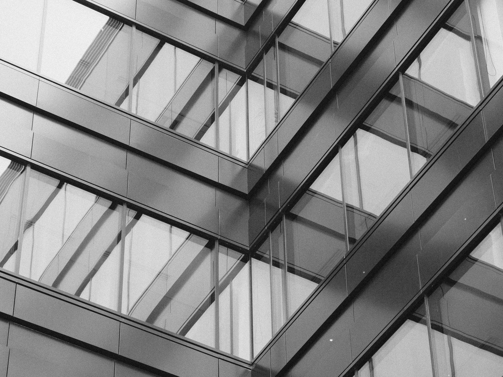Close view of a multi-storey glass facade with horizontal metal panels and dark mullion lines.