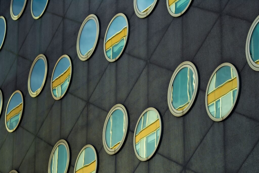 Dark metal-clad facade with circular aluminum-framed windows and reflective glass.