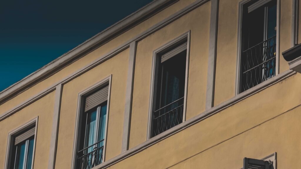 Sunlit exterior building facade with window perimeters and exposed weather joints.