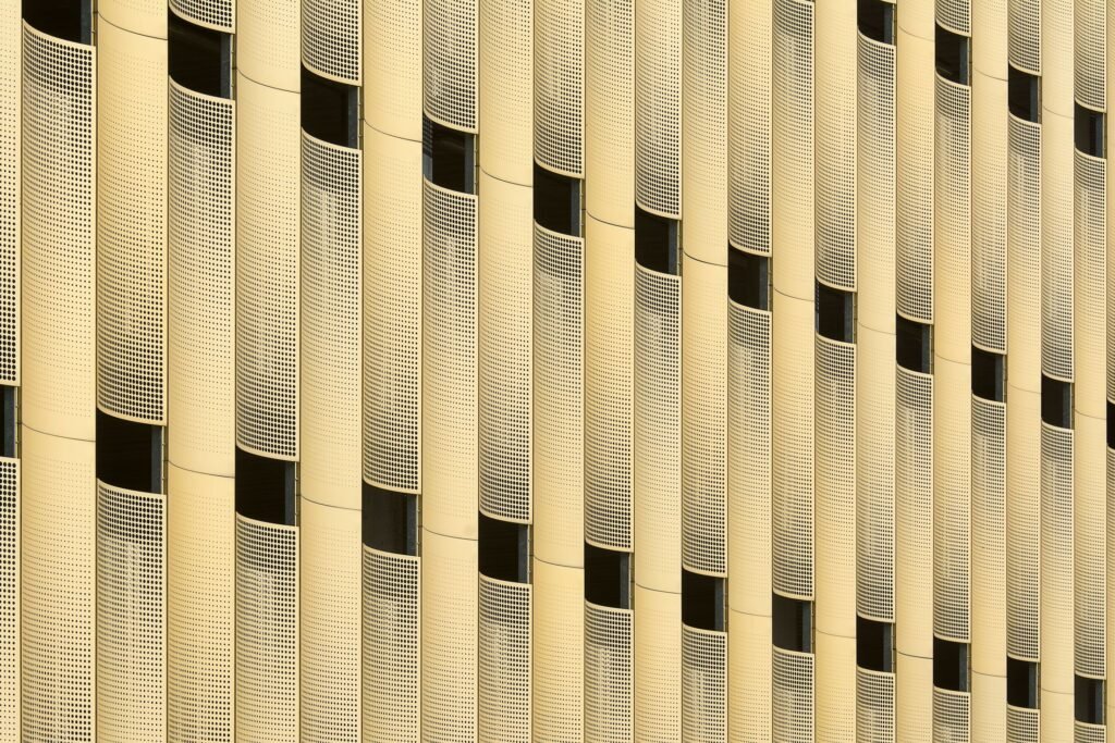 Close-up of a gold perforated metal building facade with vertical panel joints.