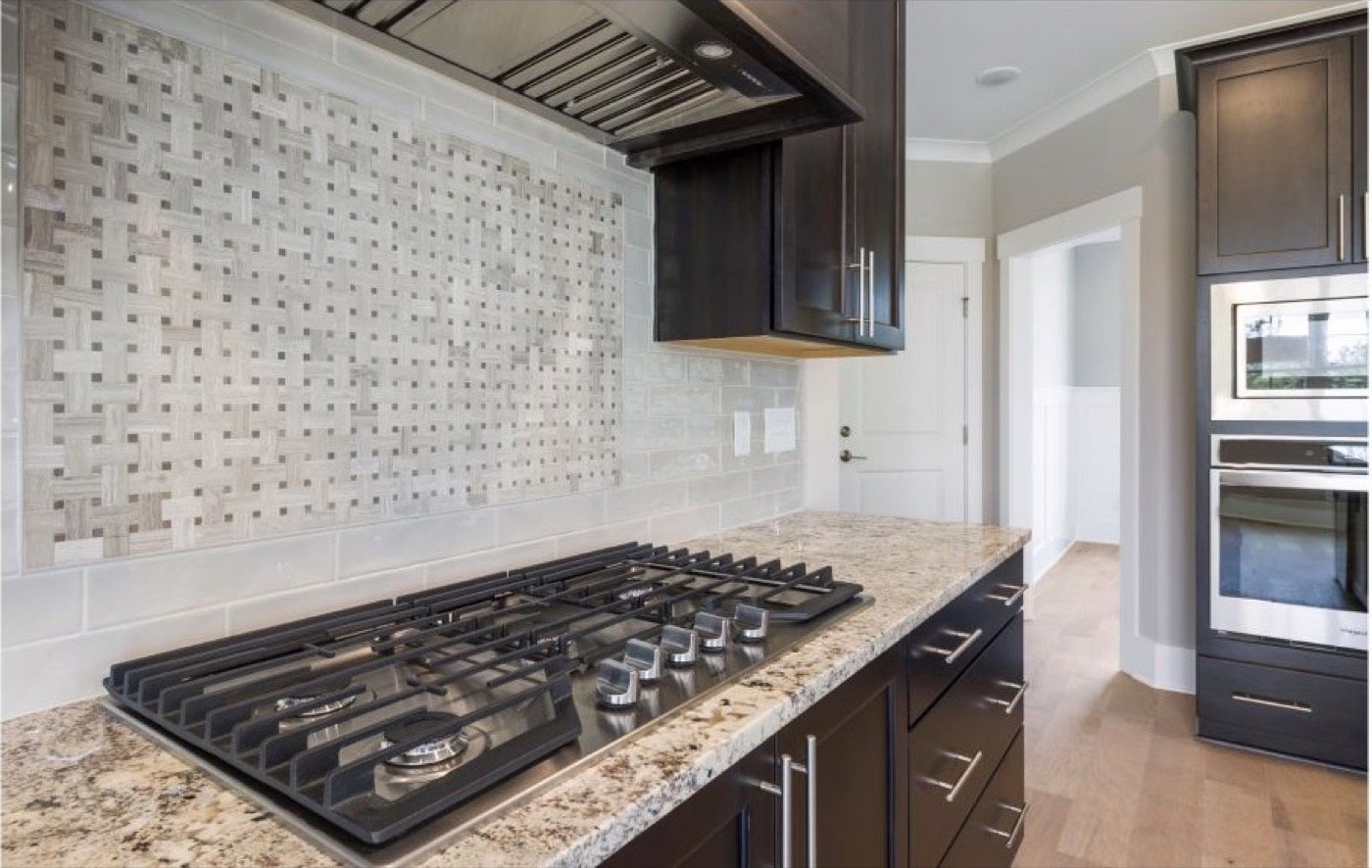 Granite countertop, tiled backsplash and kitchen worktop in a finished interior.